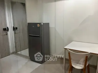 Modern apartment interior with fridge and minimalist dining area.