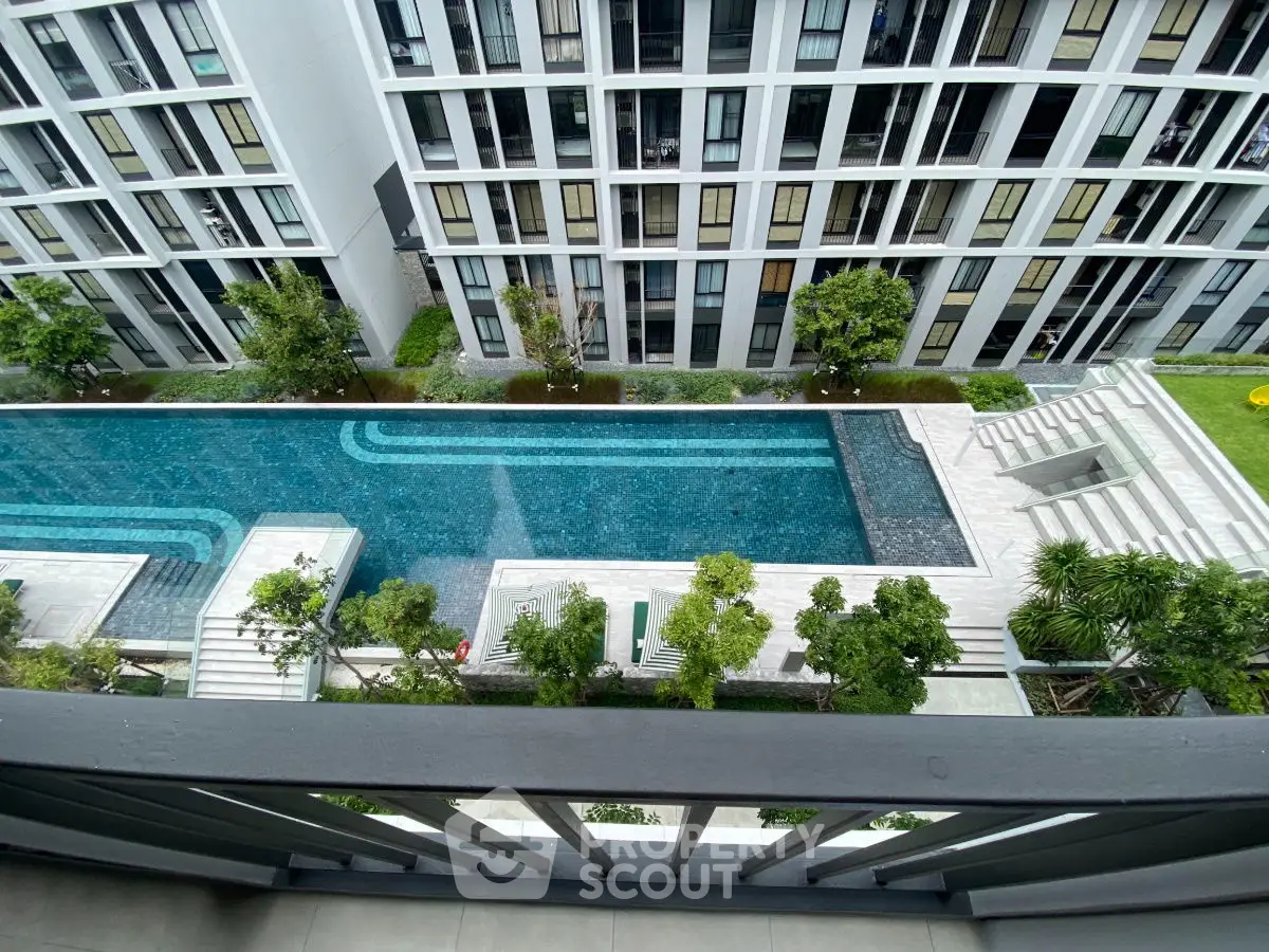 Luxurious condominium with stunning pool view from balcony, modern architecture and lush greenery.