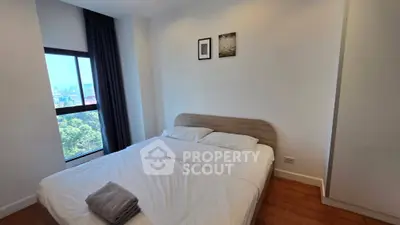 Spacious bedroom with large window offering stunning city views, featuring a cozy double bed and modern decor.