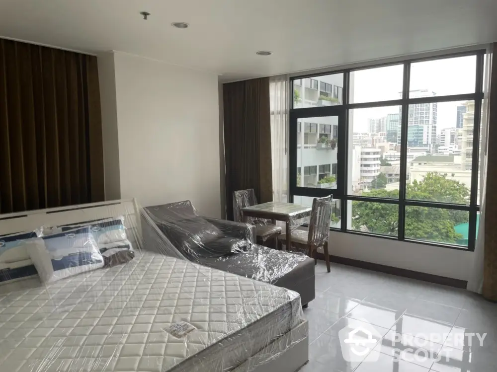 Spacious modern bedroom with large windows offering stunning city views