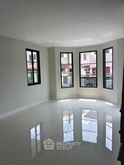Spacious and bright living room with large windows and glossy tiled floor in modern home.
