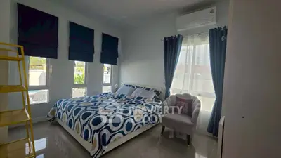 Spacious bedroom with modern decor and large windows for natural light.