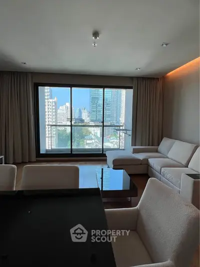 Spacious living room with modern furniture and stunning city view through large windows.