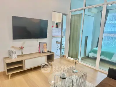 Modern living room with TV, wooden furniture, and glass doors leading to a cozy bedroom.