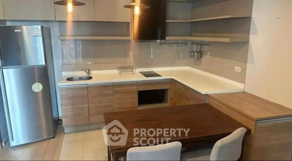Modern kitchen with sleek cabinetry and dining area, featuring built-in appliances and stylish lighting.