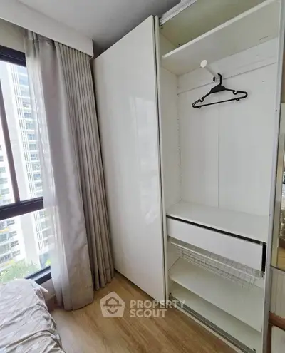 Modern bedroom with sleek wardrobe and large window offering city view