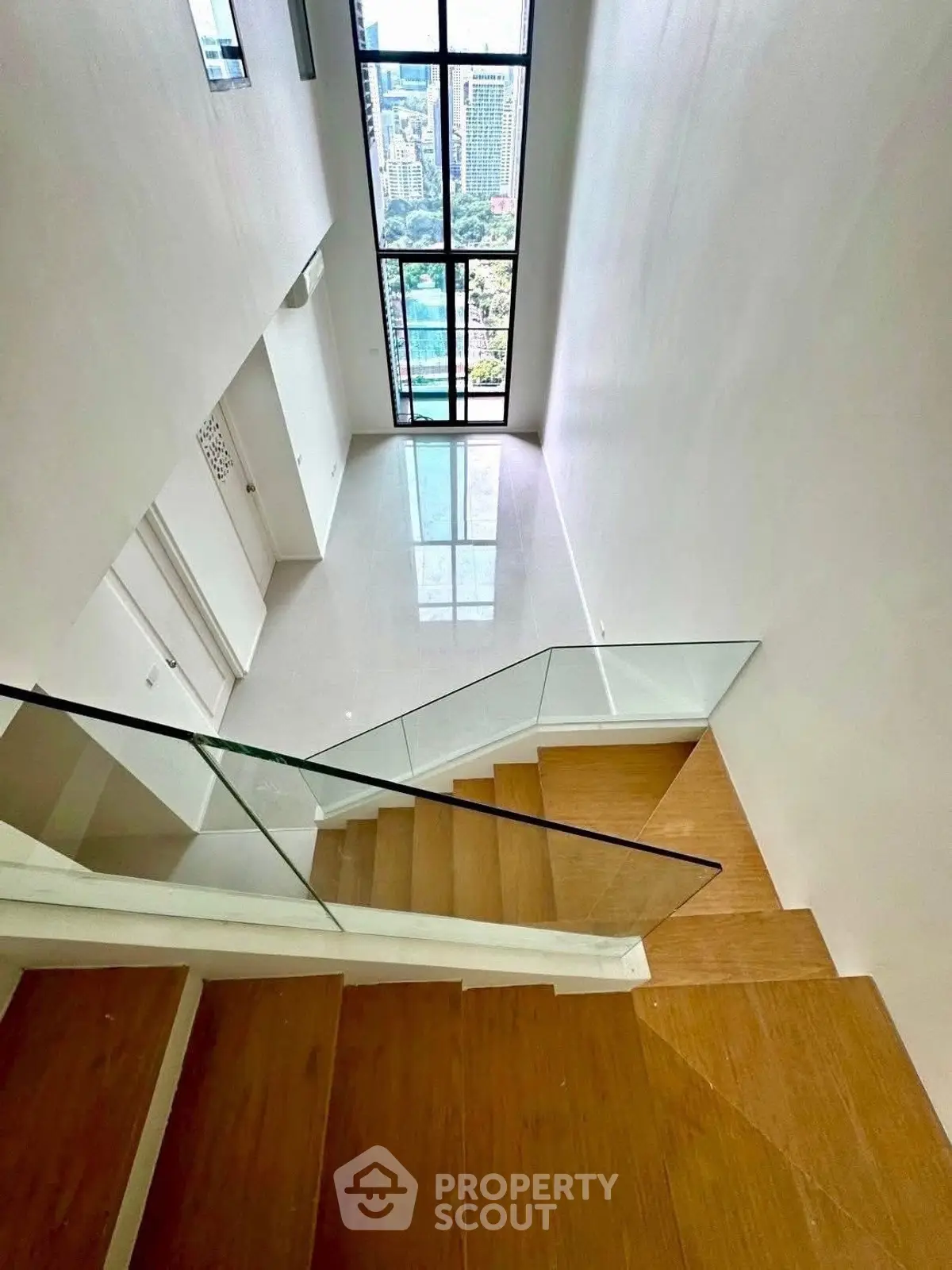 Modern duplex with wooden stairs and large windows offering stunning city views.