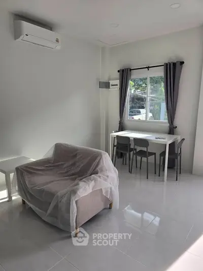 Modern living room with air conditioning and dining area, featuring sleek furniture and natural light.