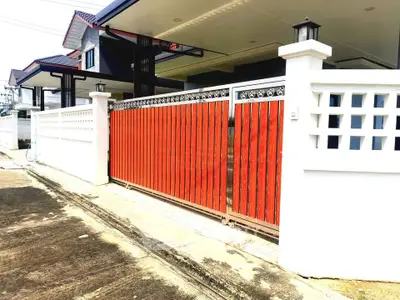 Modern house exterior with stylish red gate and white fence in a suburban neighborhood.