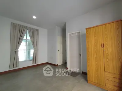 Spacious bedroom with natural light and wooden wardrobe