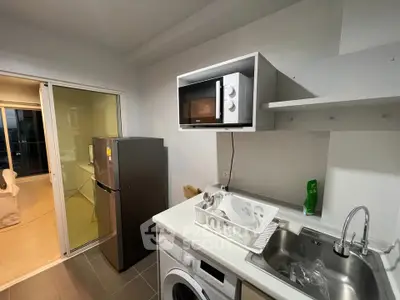 Modern kitchen with sleek appliances and open layout, featuring a microwave, fridge, and washing machine.
