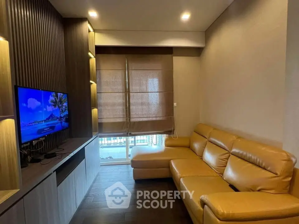 Modern living room with cozy leather sofa and built-in TV unit, perfect for relaxation and entertainment.