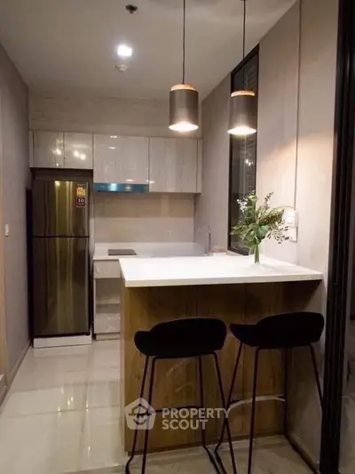 Modern kitchen with sleek design, featuring a breakfast bar and stylish lighting.