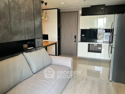 Modern living room with sleek kitchen, stylish sofa, and contemporary design elements.