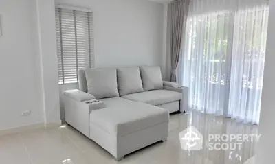 Bright and airy living room with modern gray sectional sofa and large windows with sheer curtains.