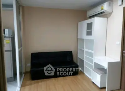 Modern living room with sleek black sofa and white shelving unit, featuring air conditioning.