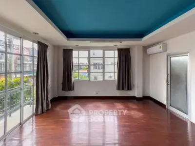Spacious living room with wooden floors and large windows offering ample natural light.