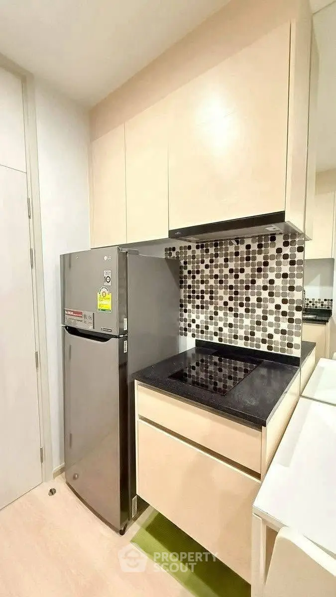 Modern kitchen with sleek appliances and stylish backsplash in compact layout.