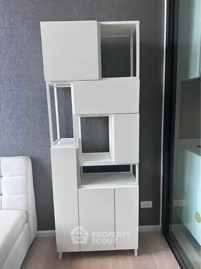 Modern white shelving unit in stylish living room with gray textured walls.
