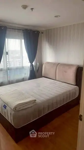 Cozy bedroom with large window and modern decor, perfect for relaxation.