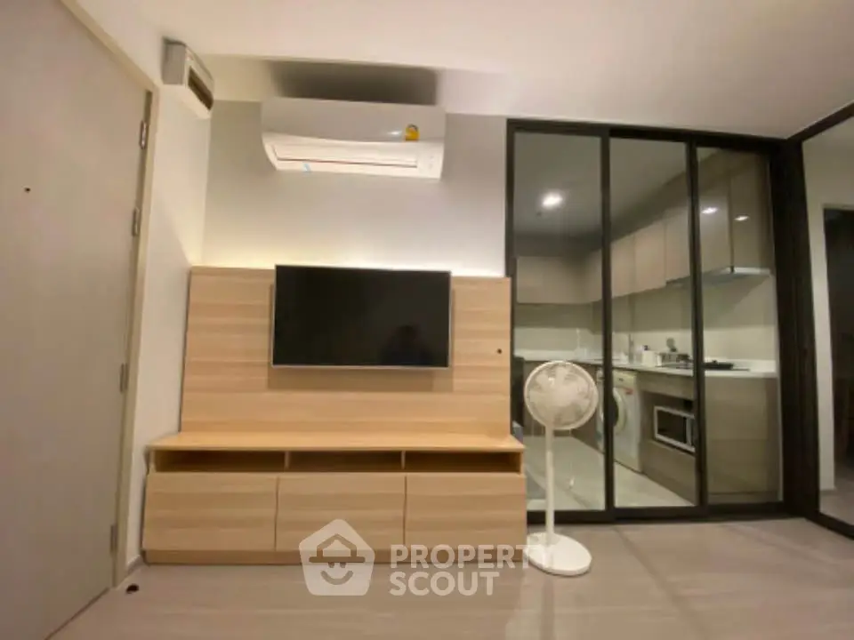 Modern living room with sleek TV unit and glass partition to kitchen