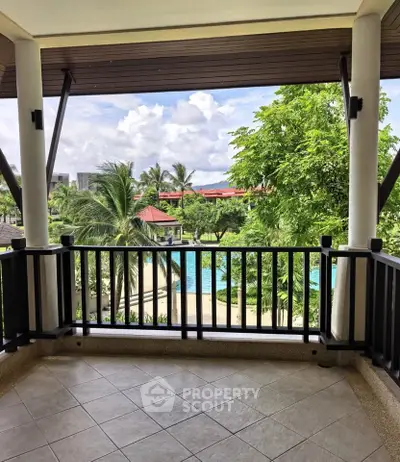Stunning balcony view overlooking lush greenery and a sparkling pool in a tropical setting.