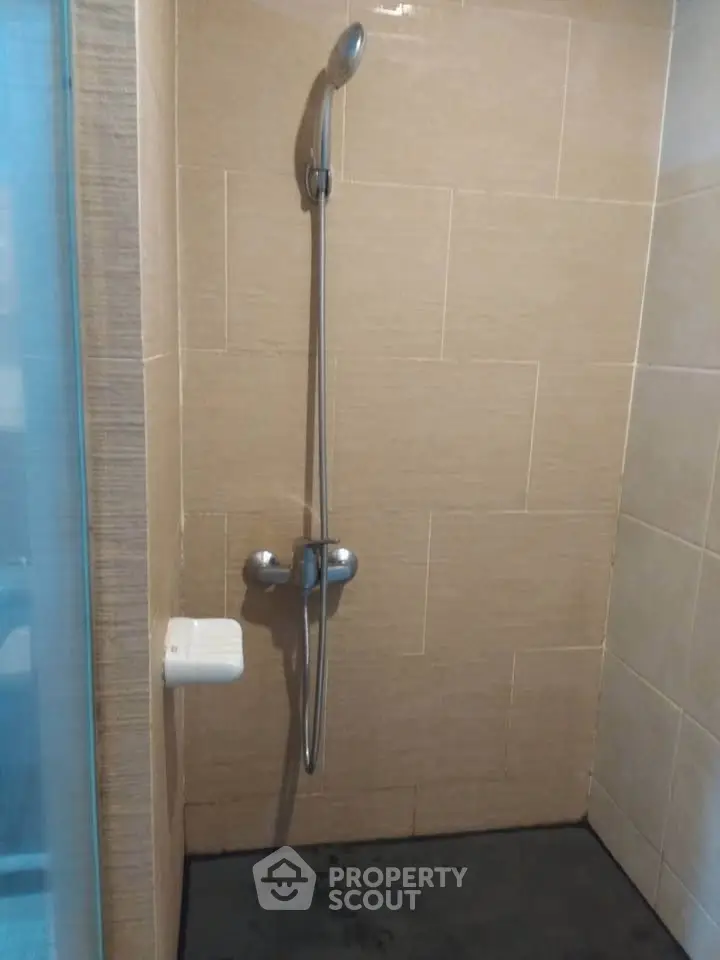 Modern shower area with sleek fixtures and beige tiles in a contemporary bathroom.