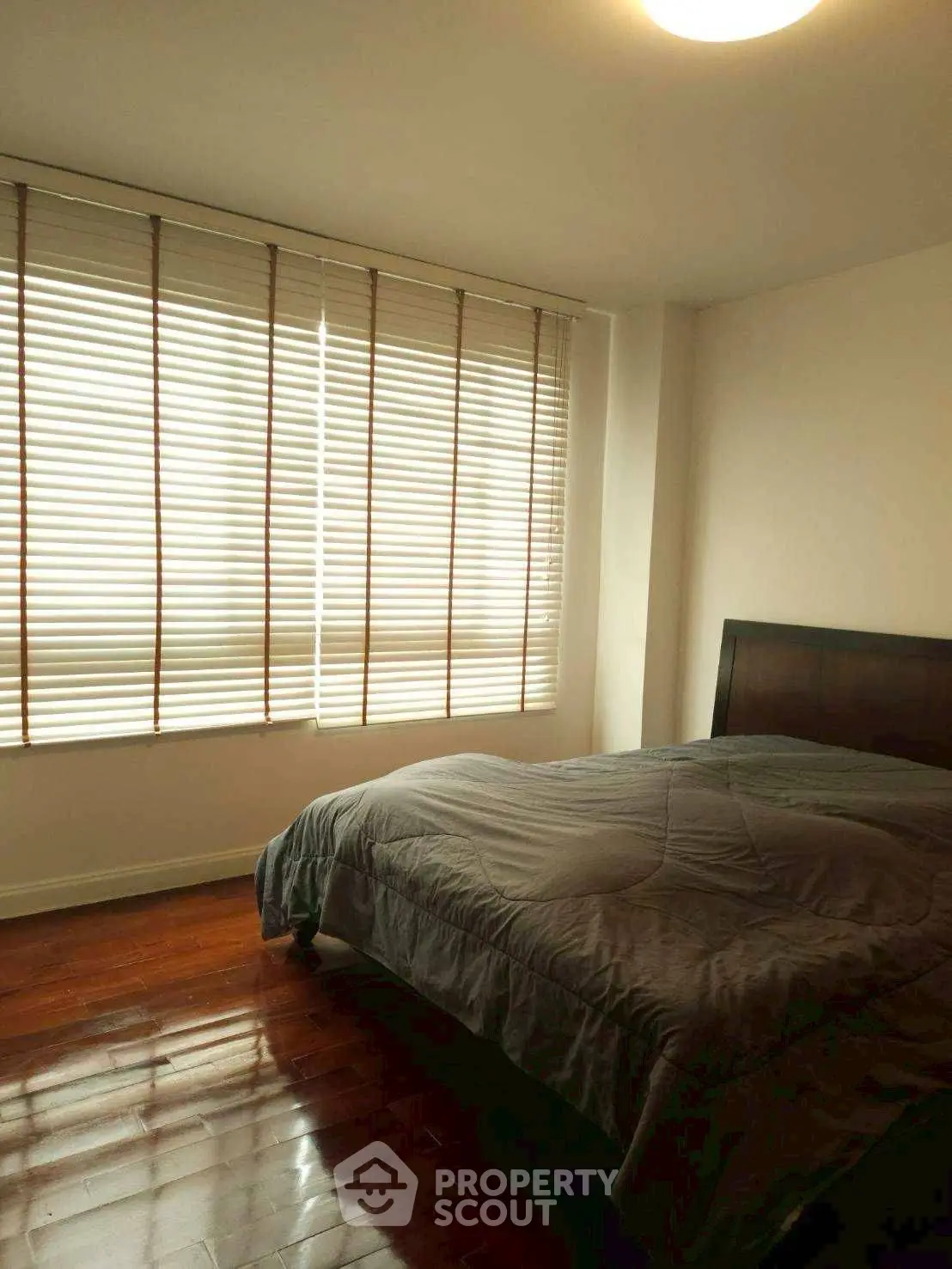 Cozy bedroom with wooden blinds and polished hardwood floors.