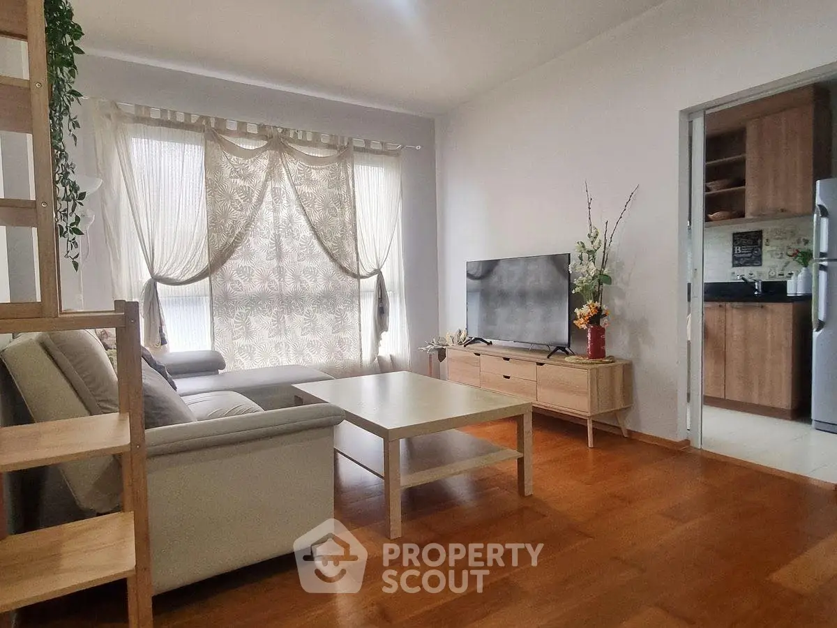 Modern living room with natural light and stylish decor, adjacent to a sleek kitchen.