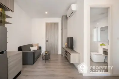 Modern living room with sleek design and open bathroom view, featuring minimalist furniture and neutral tones.