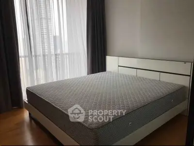 Spacious bedroom with modern bed and large window offering city views.