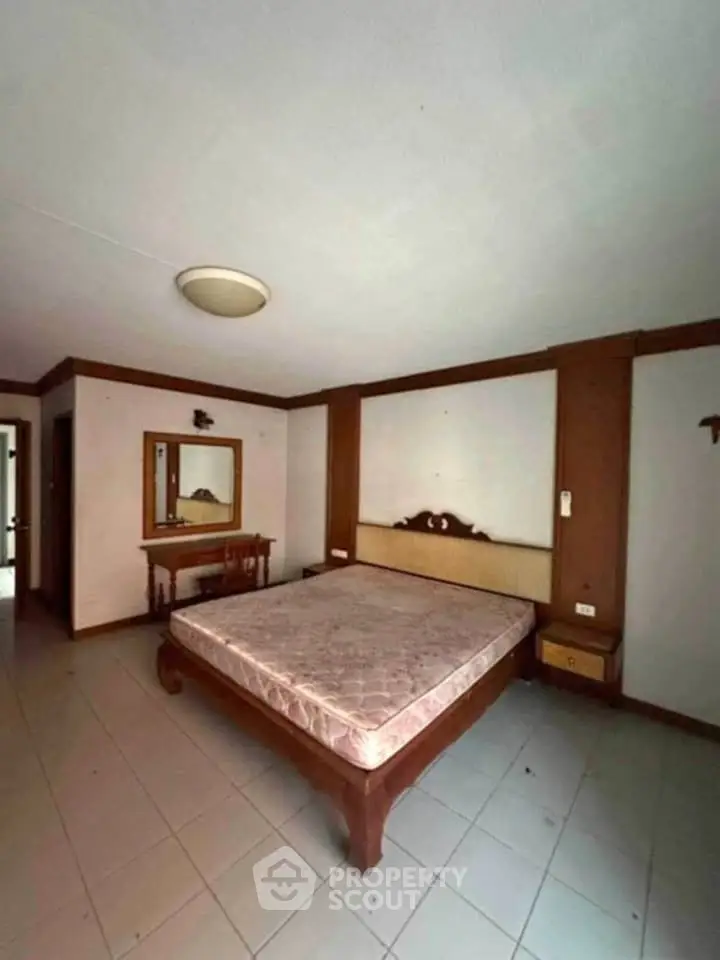 Spacious bedroom with wooden furniture and large mirror, ideal for cozy living.