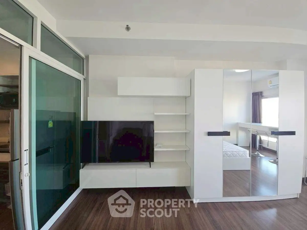 Modern living room with sleek furniture and large TV in a stylish apartment.