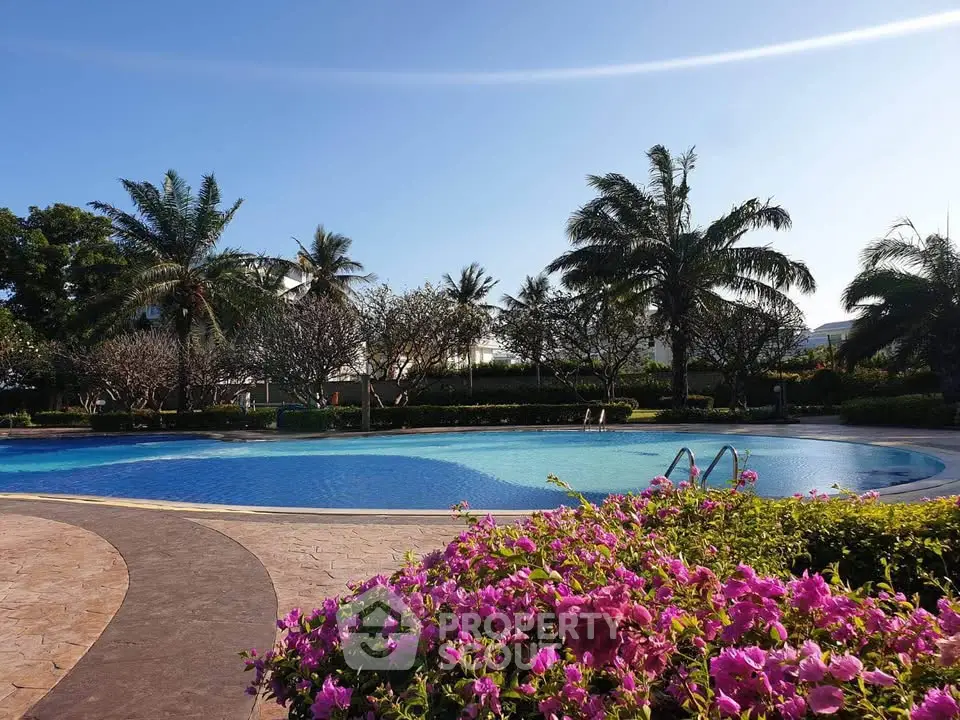 Stunning poolside view with lush greenery and vibrant flowers, perfect for relaxation and leisure.