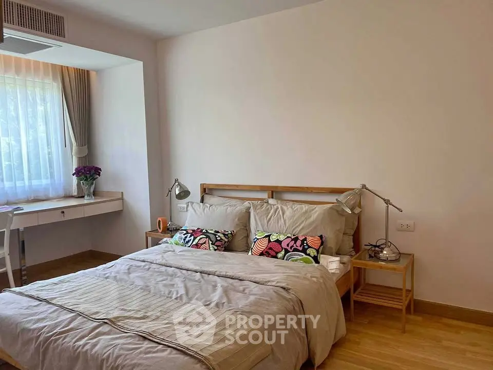 Cozy bedroom with natural light, wooden flooring, and stylish decor for a serene living experience.