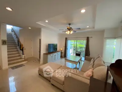 Spacious living room with modern decor and natural light, featuring a cozy sectional sofa and stylish ceiling fan.