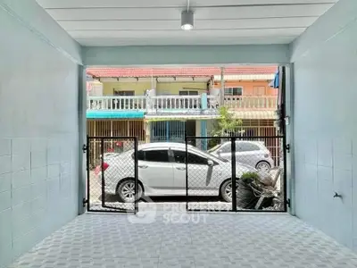 Spacious garage with secure gate and view of residential street, ideal for parking or storage.