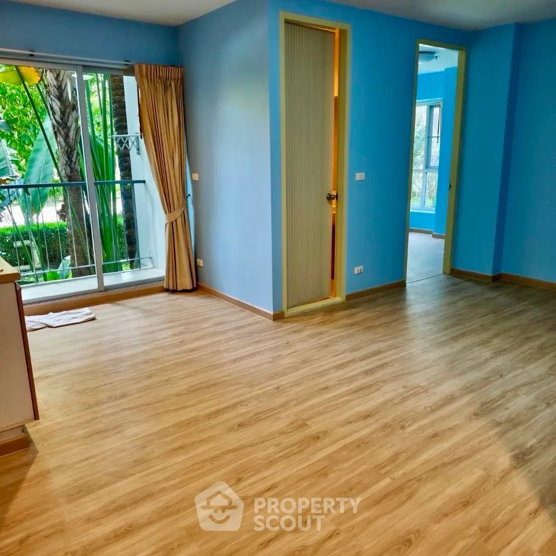 Spacious living area with wooden flooring and large windows in a modern apartment.