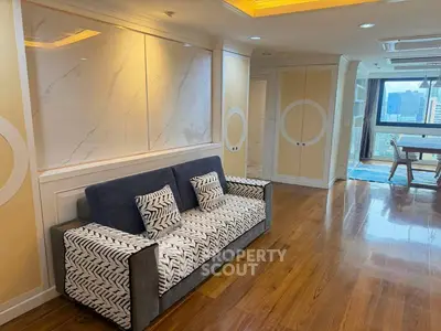 Stylish living room with modern sofa and elegant wooden flooring, featuring a bright window view.