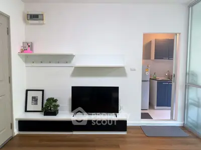 Modern living room with sleek TV setup and glimpse of stylish kitchen