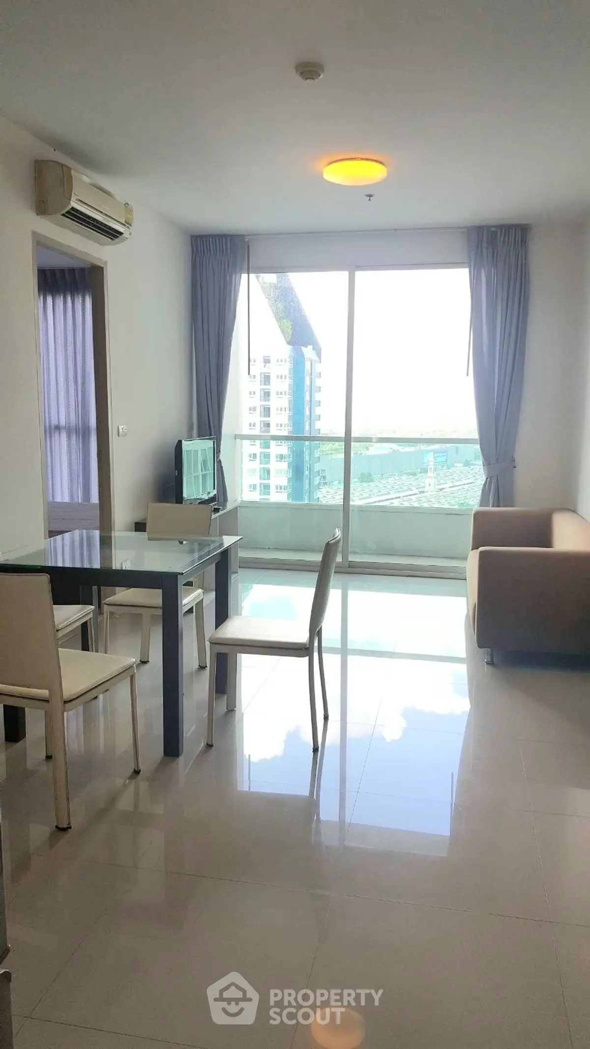 Modern living room with large window offering city view, sleek furniture, and air conditioning.