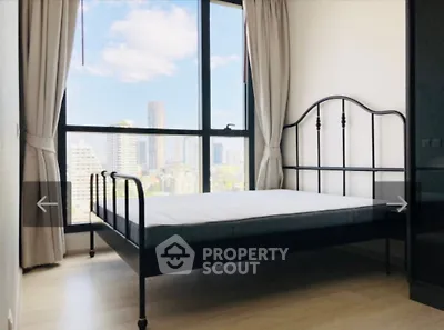 Bright bedroom with large window offering stunning city views and modern metal bed frame.