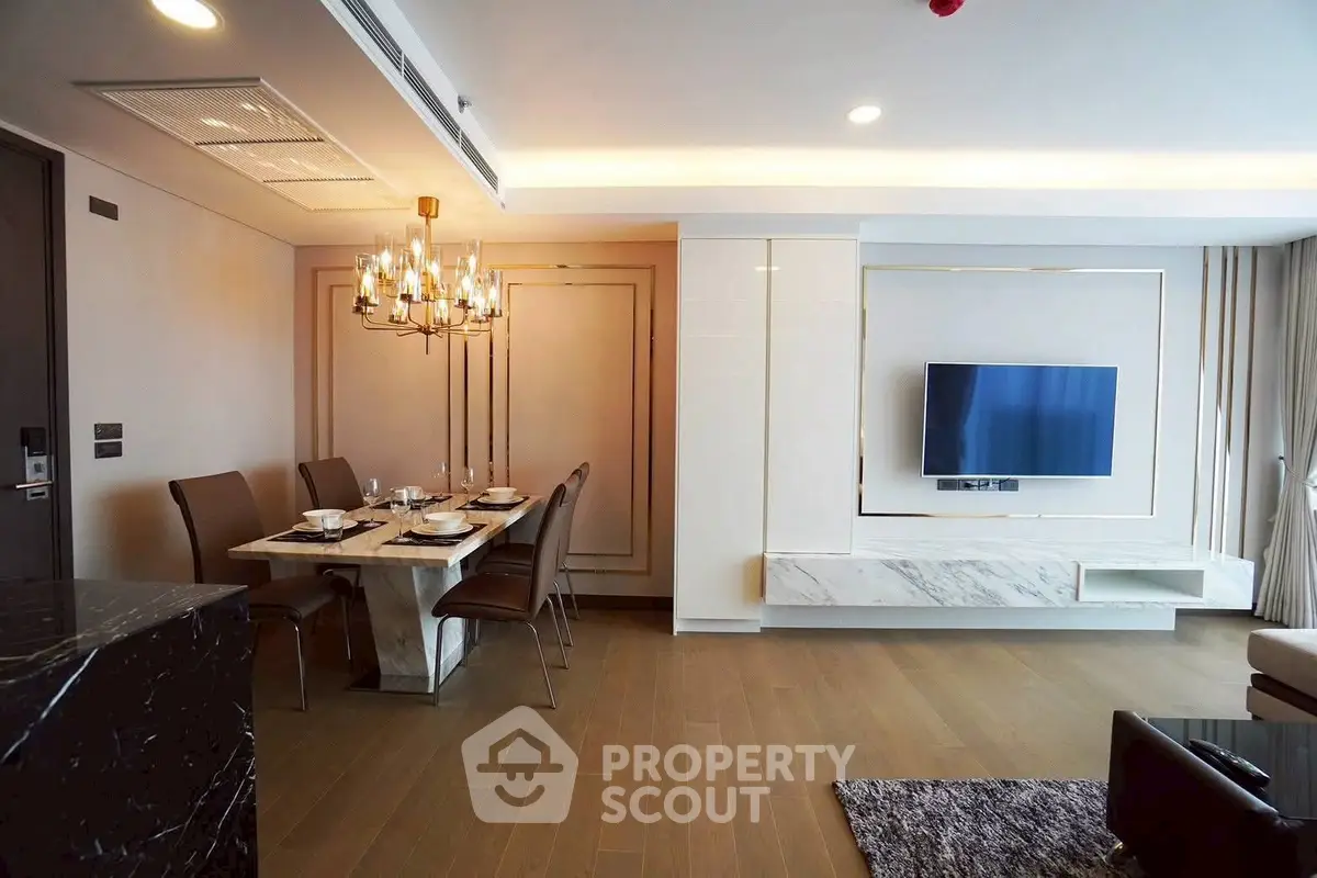 Luxurious modern living room with elegant dining area and mounted TV, featuring stylish lighting and wooden flooring.