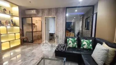 Stylish living room with modern decor and open kitchen layout, featuring marble flooring and cozy seating.