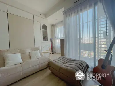 Cozy living room with natural light and balcony view, featuring modern furniture and guitar.