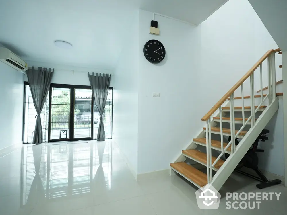 Modern minimalist living room with staircase and large windows