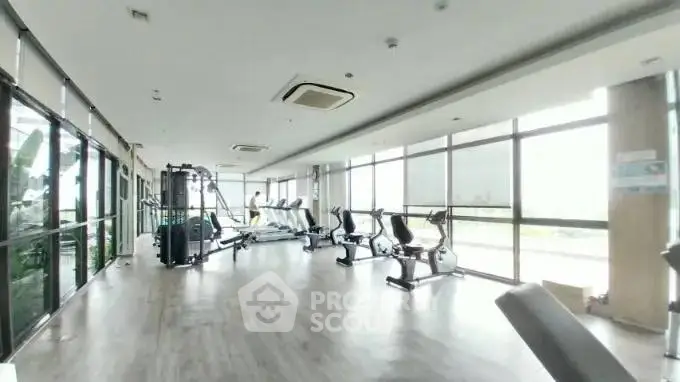 Spacious modern gym with large windows and fitness equipment
