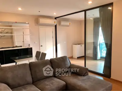 Modern living room with plush sofa and glass partition leading to balcony