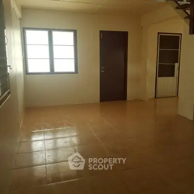 Spacious empty room with tiled floor and large windows, ideal for customization.