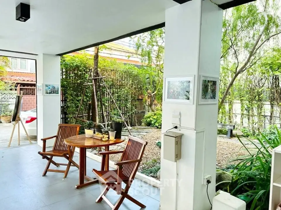 Charming outdoor patio with wooden furniture and lush garden view, perfect for relaxation and entertaining.